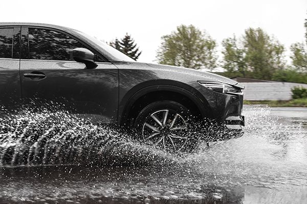 Car driving through standing water on a wet road, splashing water from the tires